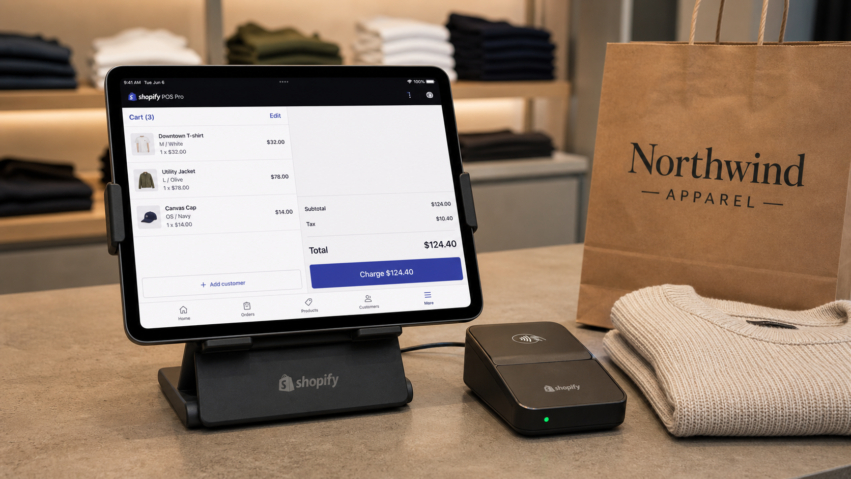 Shopify POS Pro app on an iPad at a retail checkout counter mid-sale with a Shopify Tap and Chip card reader beside it