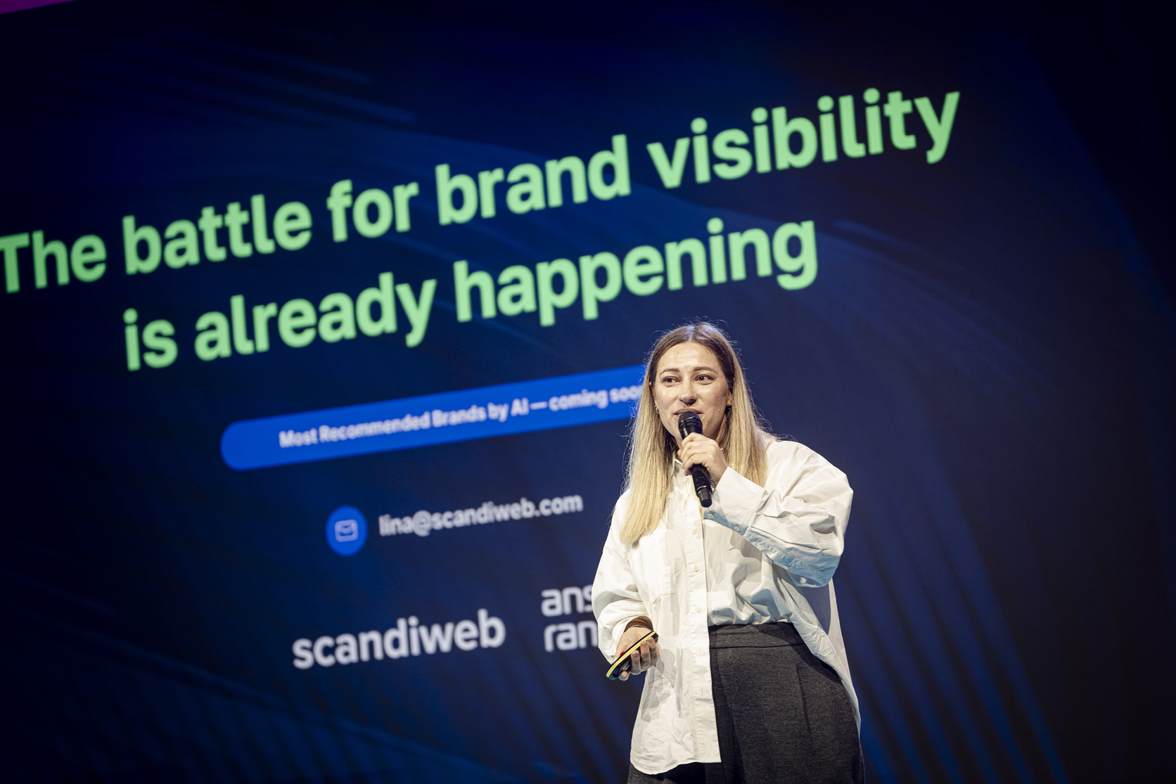 Lina Ivanova on stage at Baltic Brand Forum in front of a slide on the battle for brand visibility